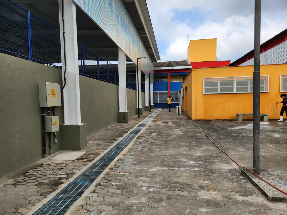 Circulação entre a quadra e o prédio escolar, com canaleta de drenagem