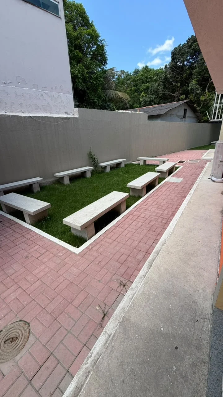Área de convívio externa com bancos de concreto e paisagismo
