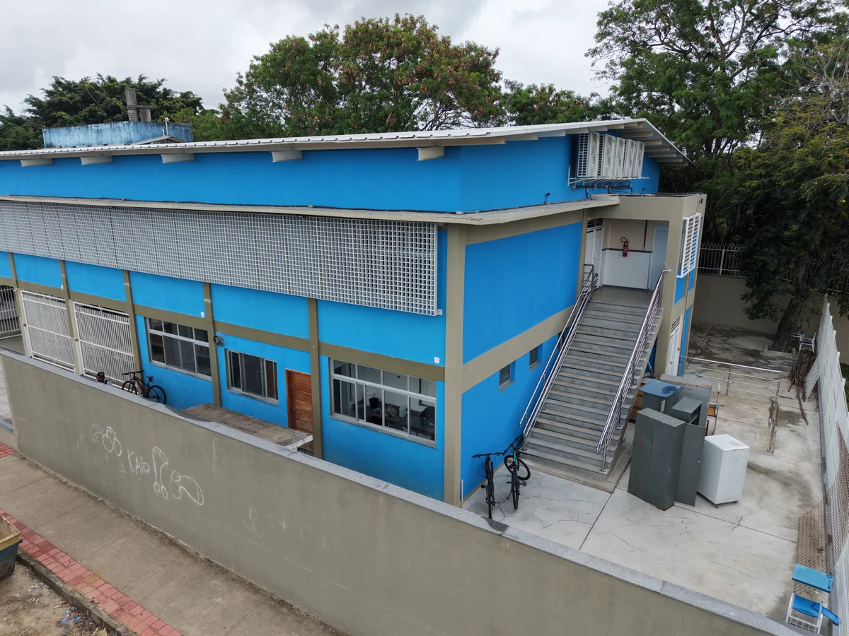 Acesso lateral do bloco escolar com escada e muro de fechamento